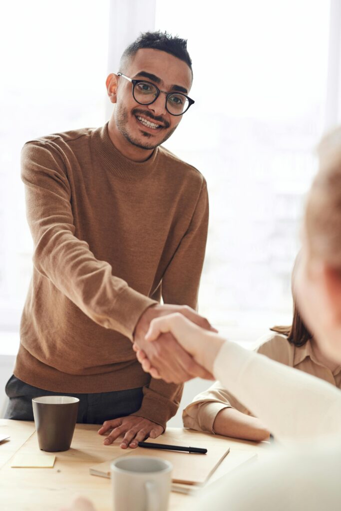 Smiling professionals engage in a welcoming handshake at a business meeting indoors.